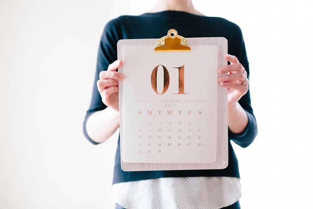 A person holding a calendar page on a clipboard