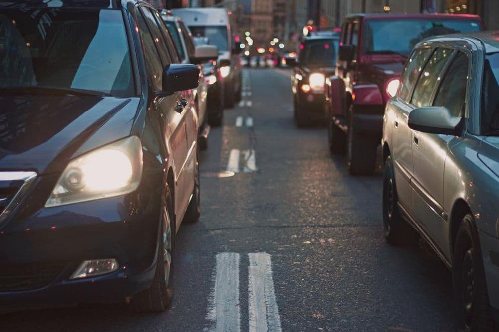 Cars queued in city traffic with headlights on