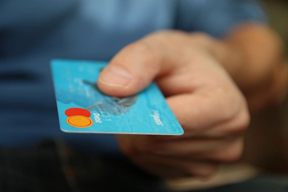 A hand holding out a payment card